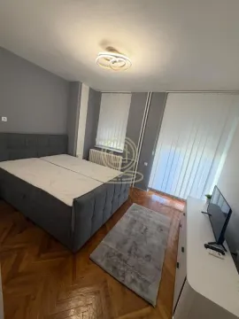 Nameštena spavaća soba sa bračnim krevetom, televizorom i parketom na podu. - image 9