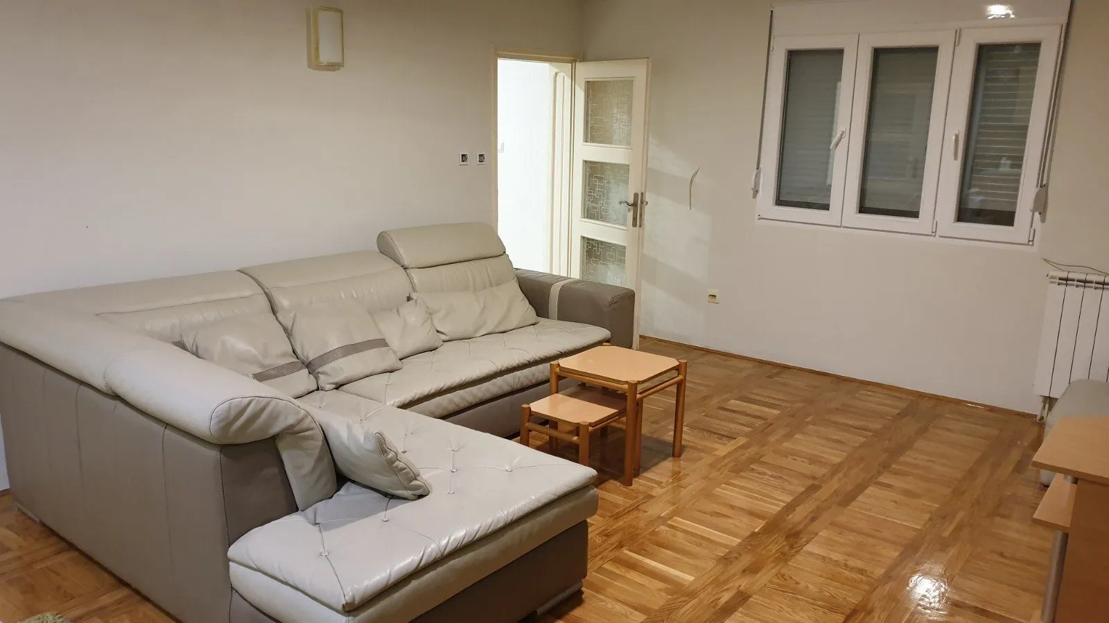 Living room with a leather corner sofa and parquet flooring.
