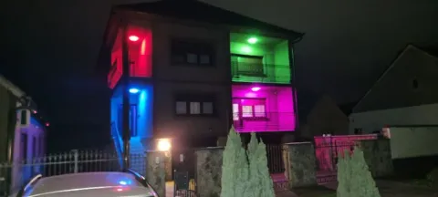 Eksterijer višespratne kuće noću sa osvetljenjem u različitim bojama. - image 10