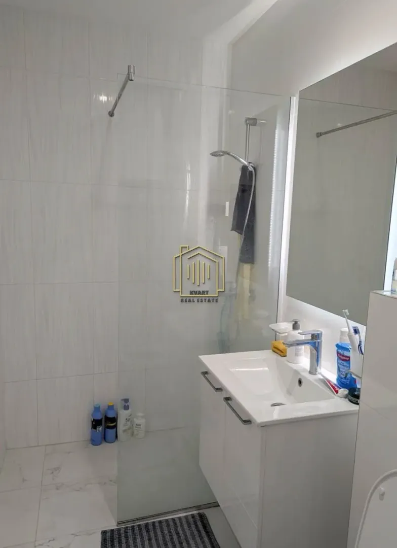 Moderno opremljeno kupatilo sa tuš kabinom i umivaonikom.