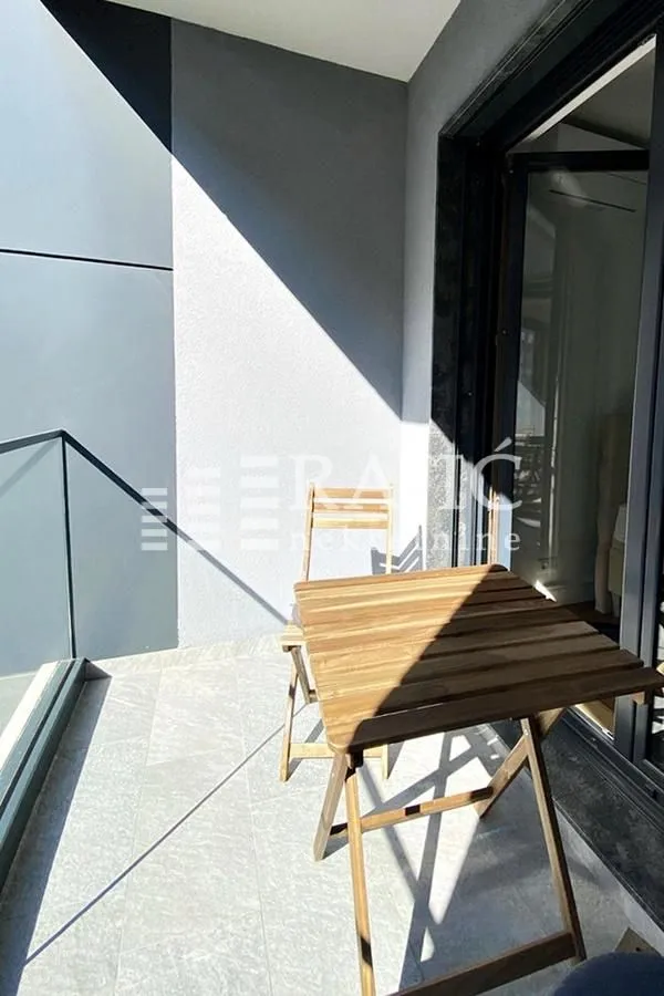 Small covered terrace with a wooden table and chair.