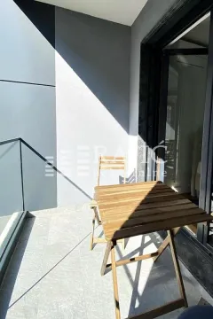 Small covered terrace with a wooden table and chair. - image 10