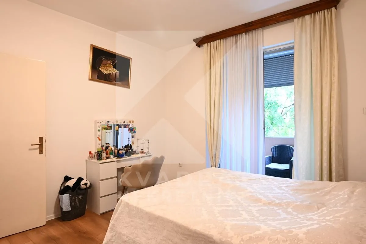 Spavaća soba sa bračnim krevetom, stočićem za šminkanje i izlazom na terasu.