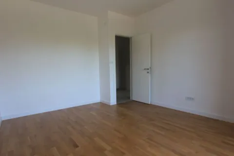 Prazna soba sa bijelim zidovima i drvenim podom. - image 6