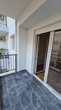 Manji popločani balkon sa crnom ogradom i izlazom u stan. - image 5