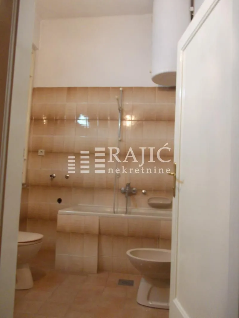 View of the bathroom with a bathtub and sanitary facilities through an open door.