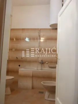 View of the bathroom with a bathtub and sanitary facilities through an open door. - image 16