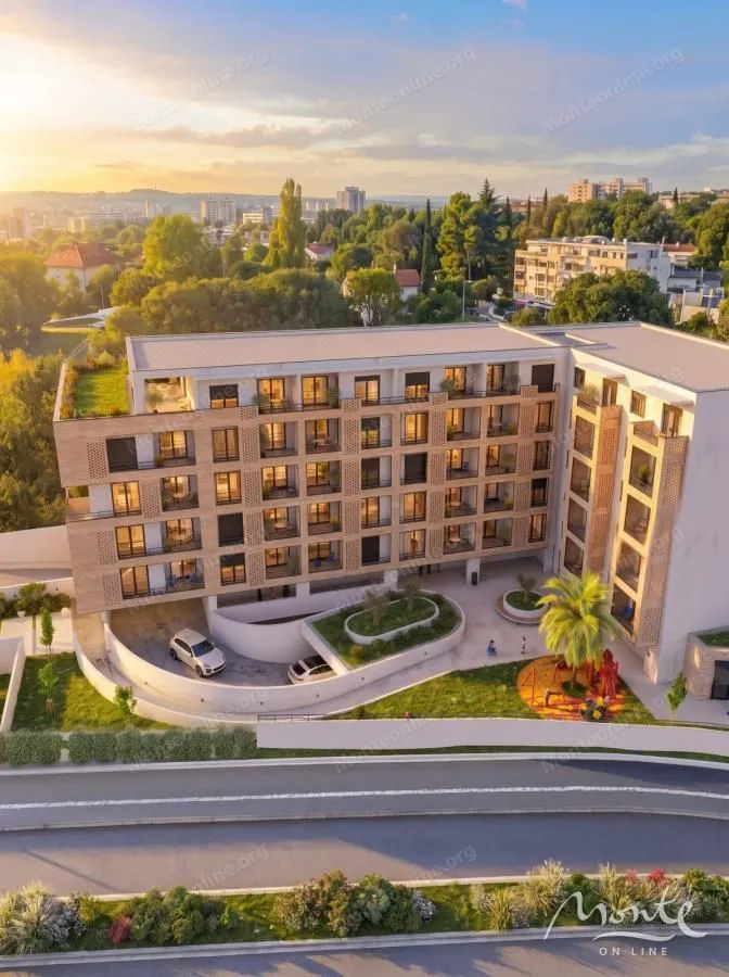 Pogled iz vazduha na spoljašnjost moderne stambene zgrade sa uređenim dvorištem i igralištem.