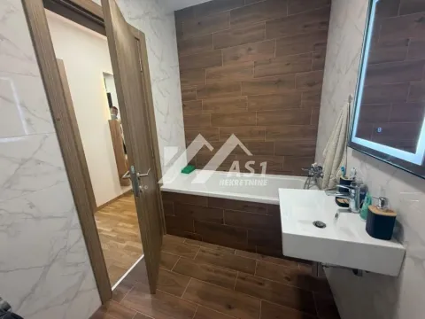 Modern bathroom with bathtub, washbasin, and wood-look tiles. - image 3