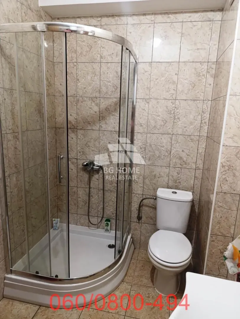 Kupatilo obloženo keramičkim pločicama sa tuš kabinom i wc šoljom.