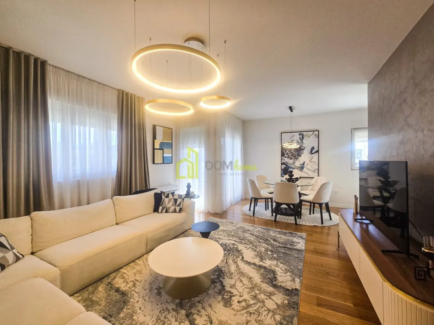 Spacious living room with a sofa, TV unit and dining area in the background.