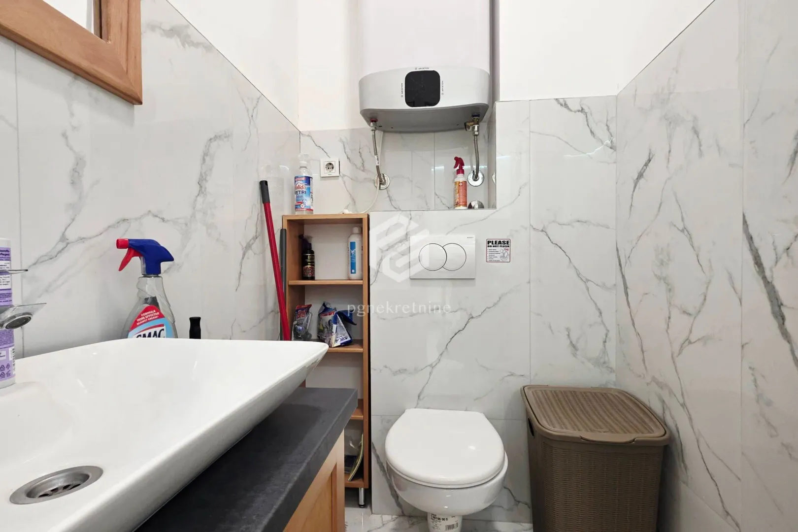 Bathroom with a washbasin, concealed toilet, and water heater.