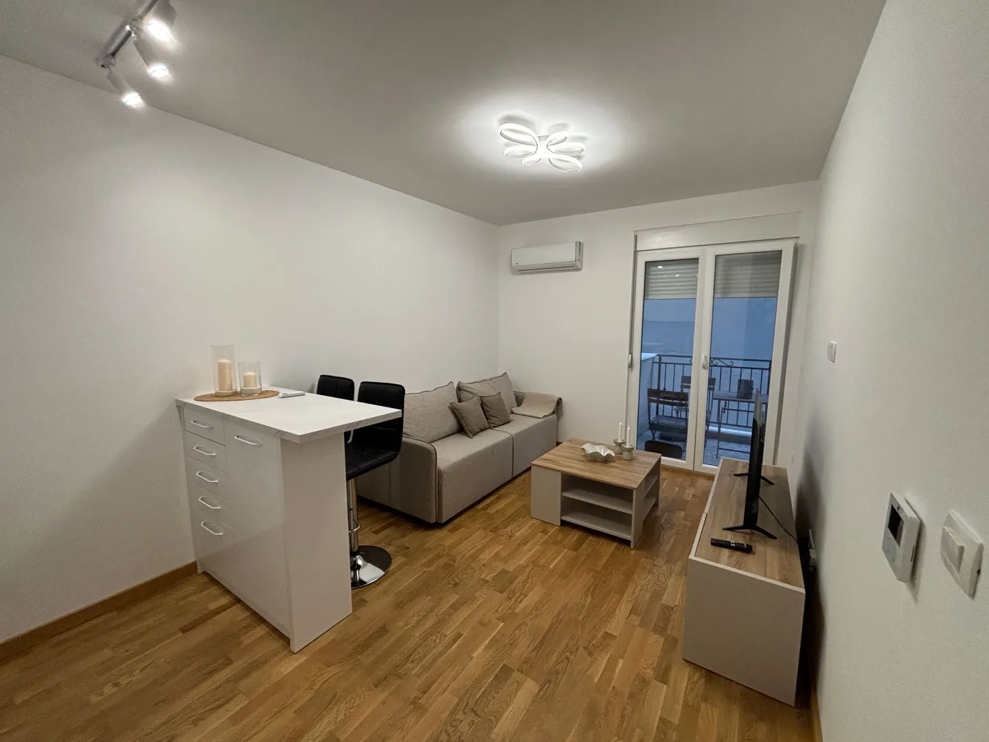 Living room with a sofa, dining table, and terrace access.