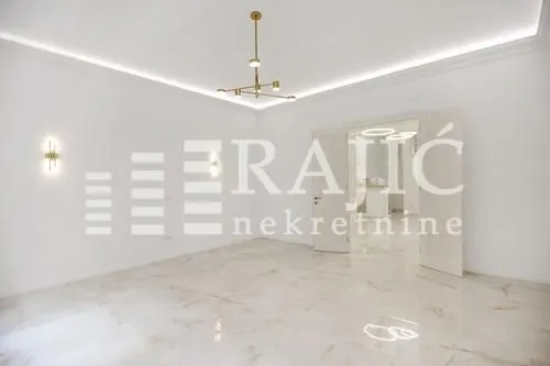 Empty living room with light floor tiles and a modern chandelier.