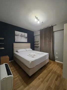 Moderna spavaća soba sa bračnim krevetom, tamnim zidom i drvenim podom. - image 4