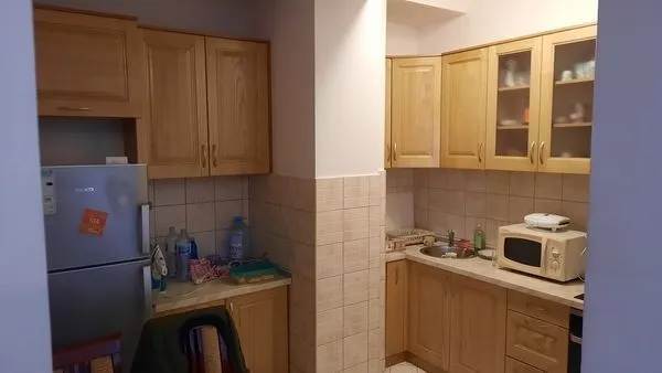 Kuhinja sa drvenim elementima, frižiderom i mikrotalasnom pećnicom.