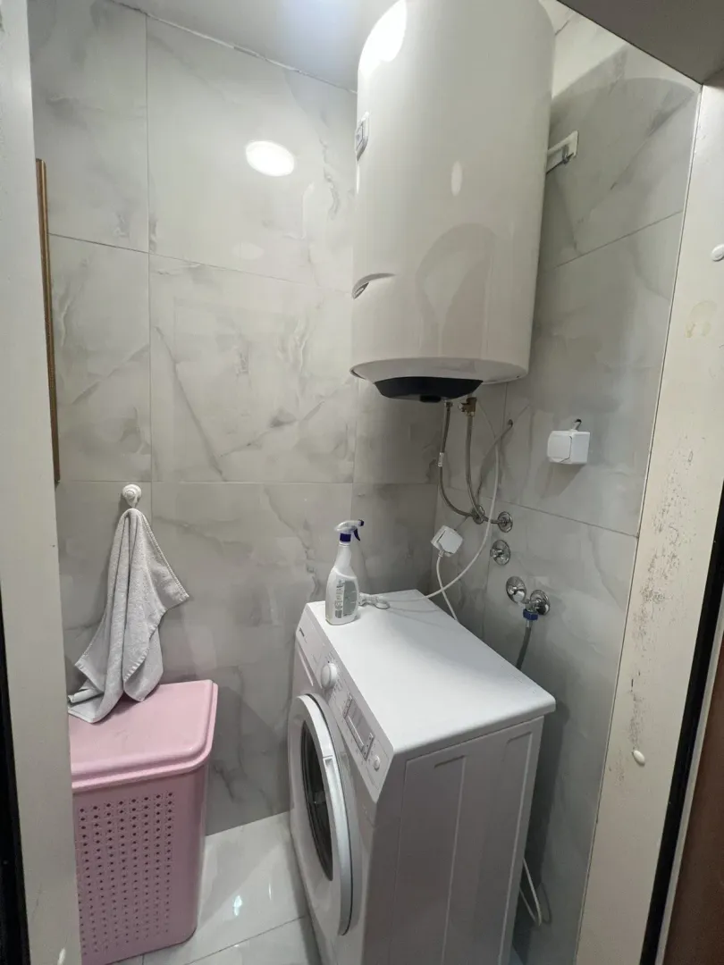 Part of the bathroom with a washing machine and water heater.