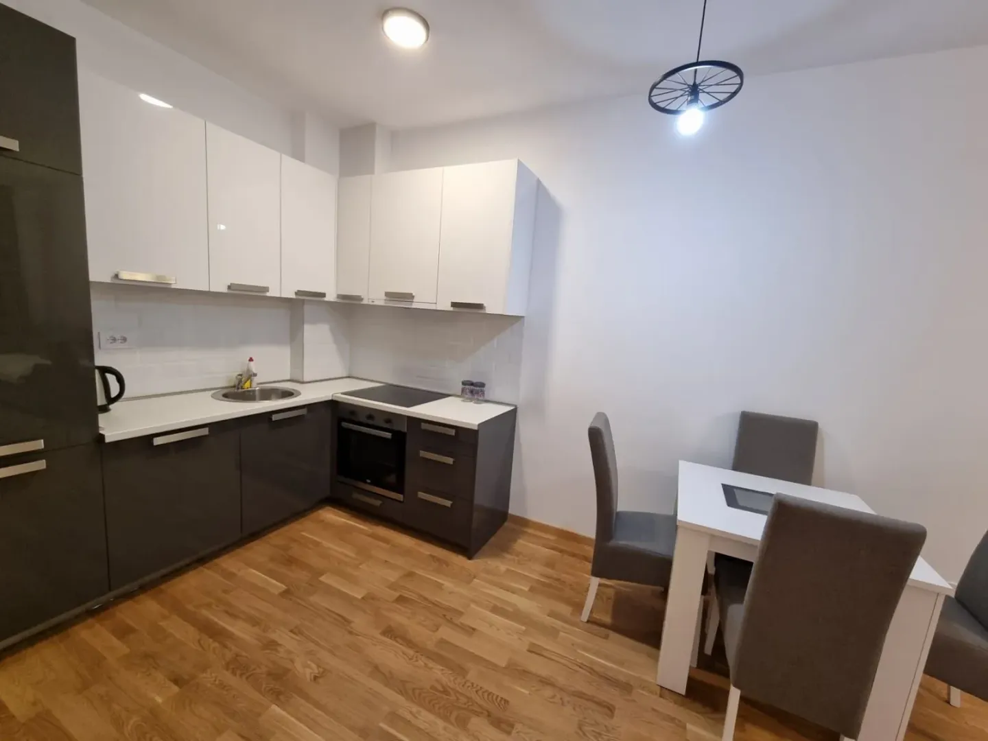 Kitchen with white and dark cabinets and a dining table with chairs.