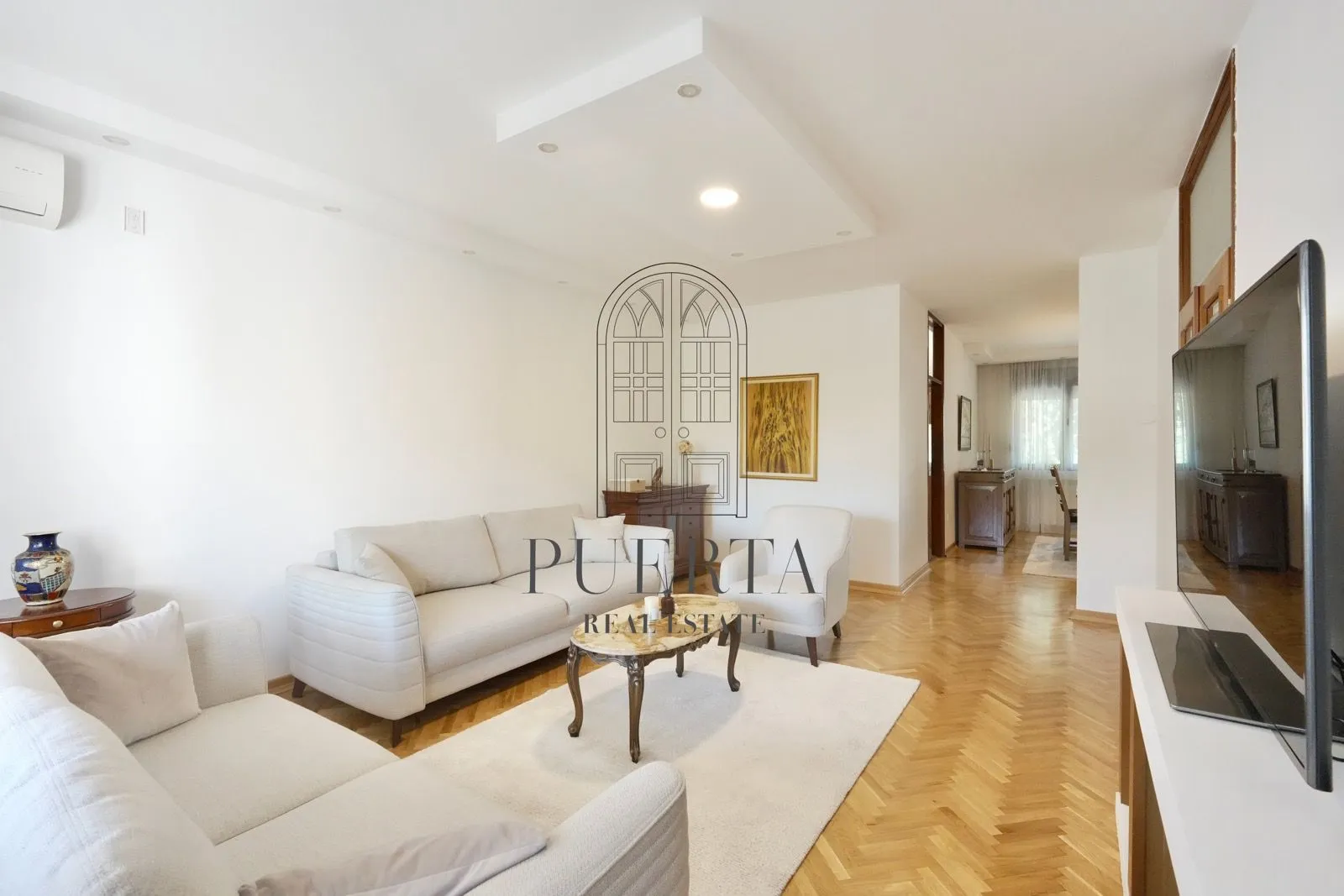 Spacious living room with sofa set and parquet flooring.