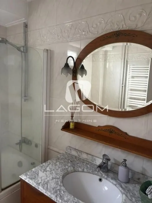 Bathroom equipped with a washbasin, a wooden-framed mirror, and a shower cabin.