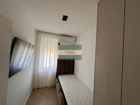 Manja spavaća soba sa krevetom, garderoberom i televizorom na zidu. - image 17