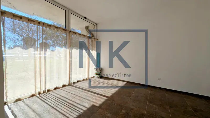 Empty room with large glass windows and tiled flooring.