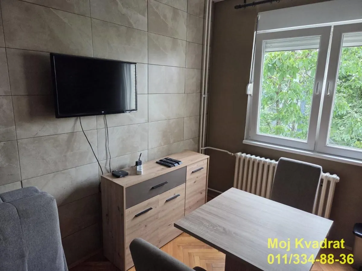 Dnevni boravak sa komodom, televizorom i trpezarijskim stolom.