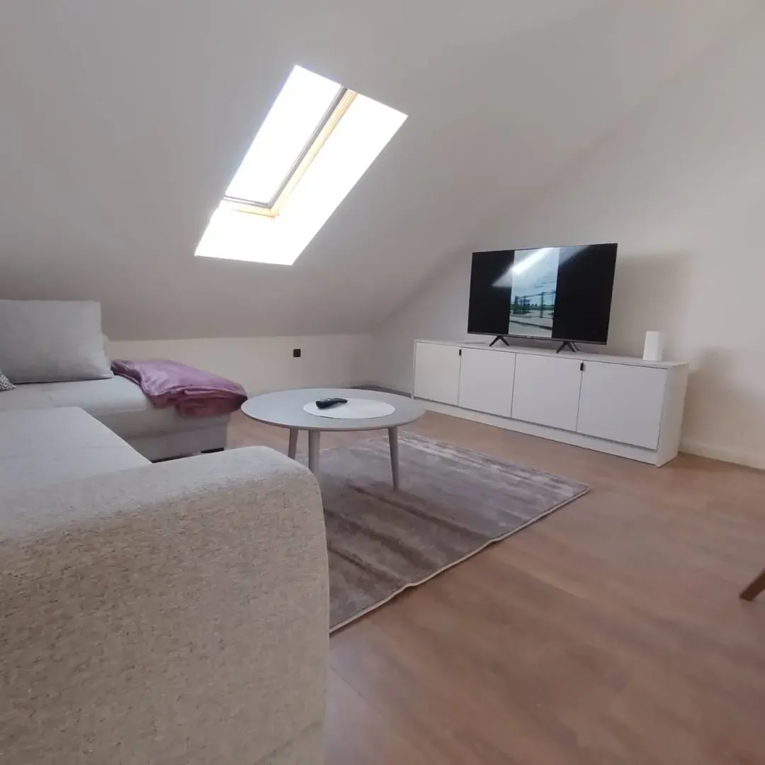 Attic living room with sofa, television, and skylight.
