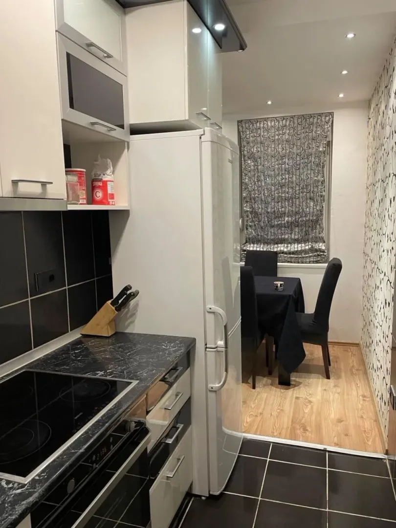 Small kitchen with white cabinets and a dining area in the background.