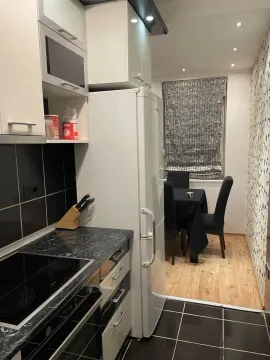 Small kitchen with white cabinets and a dining area in the background. - image 5