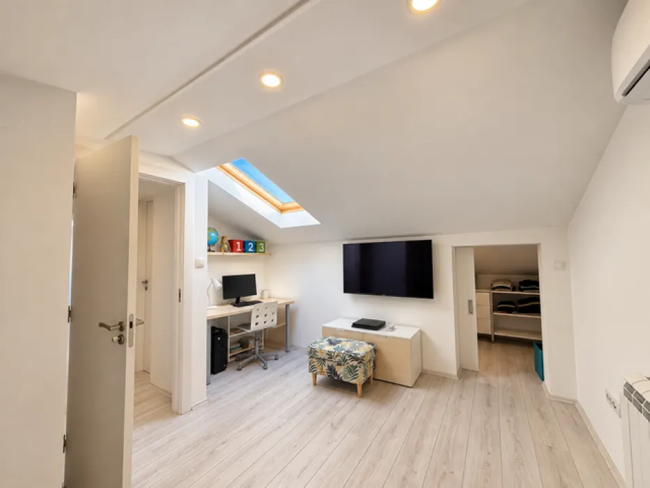 Attic space furnished as a study and living area with a skylight.