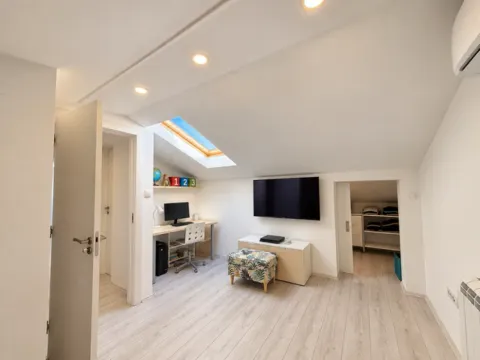Attic space furnished as a study and living area with a skylight. - image 13
