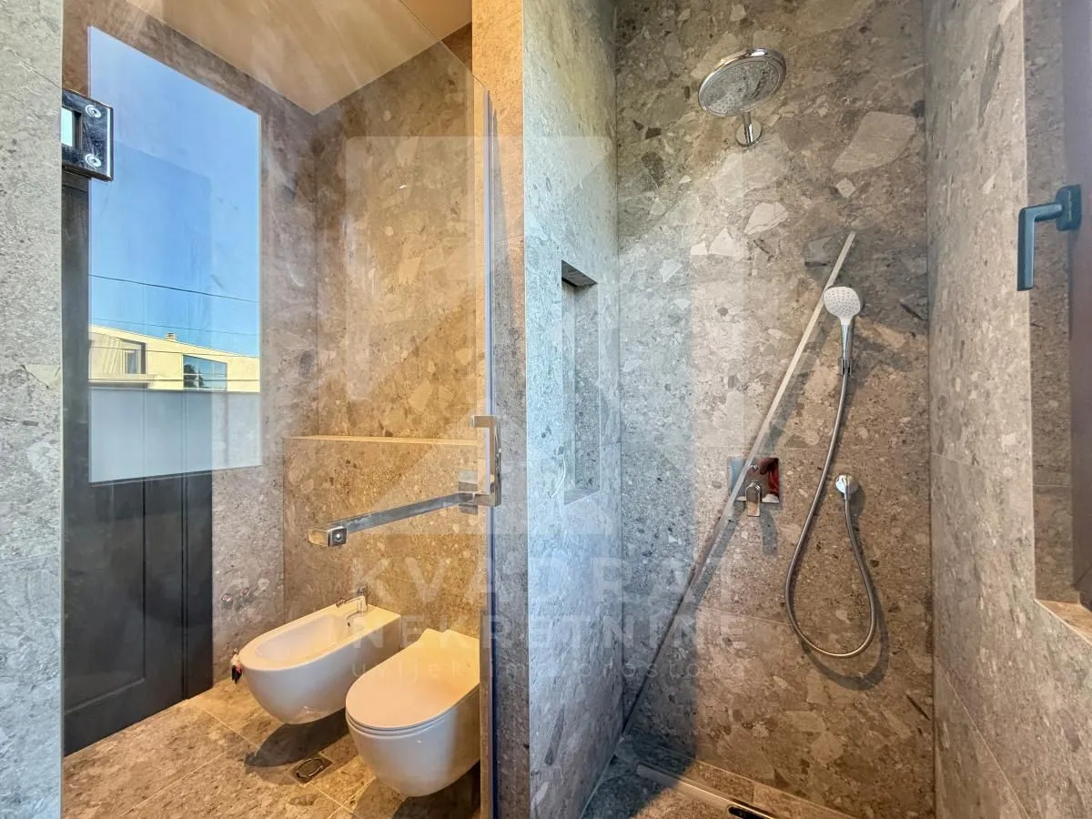 Modern bathroom tiled with grey tiles featuring a walk-in shower.