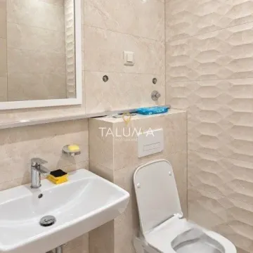 Smaller bathroom with a sink, mirror, and toilet lined with ceramic tiles. - image 4