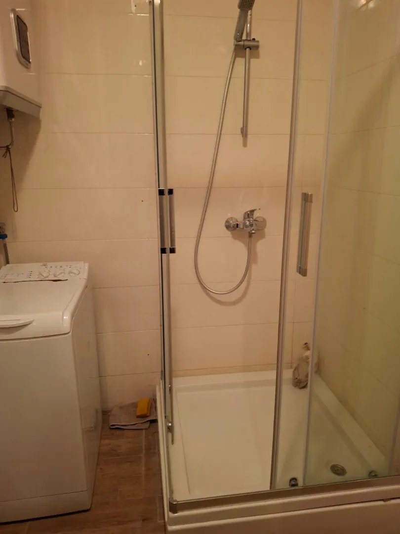 Smaller bathroom with a shower cabin and washing machine.