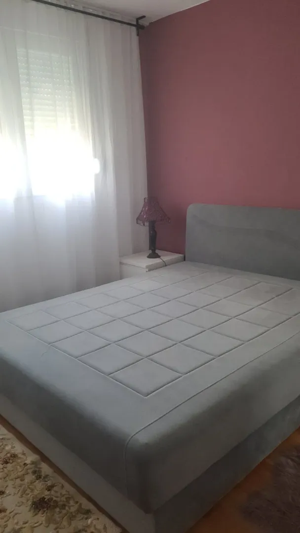 Simply furnished bedroom with a grey bed and a nightstand.