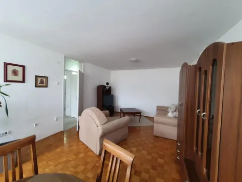 Dnevna soba sa garniturom za sedenje, televizorom i parketom na podu. - image 4