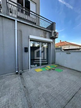 View of the paved courtyard and the entrance to the building with glass doors. - image 4