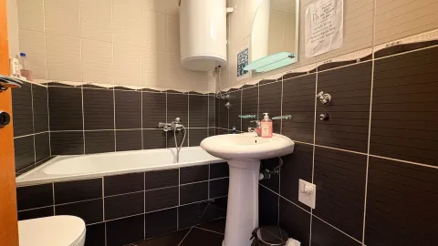 Bathroom equipped with a bathtub, washbasin, and water heater. - image 8