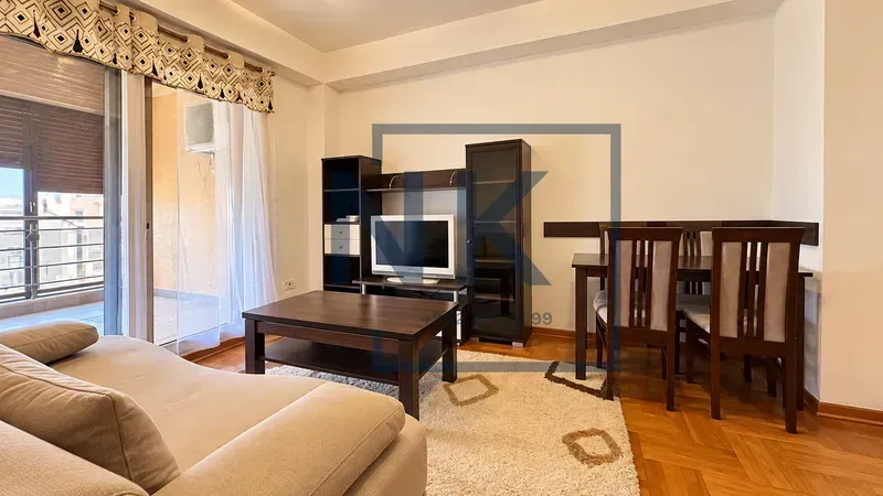Dnevna soba sa garniturom, televizorom i trpezarijskim stolom.