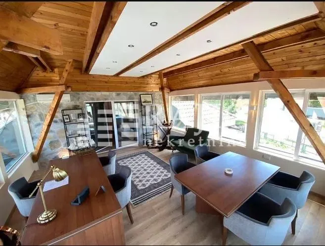 Spacious living room with wooden roof beams and a dining table.