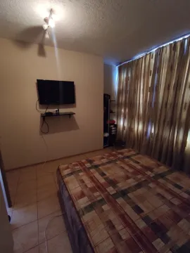 Jednostavna spavaća soba sa krevetom sa kariranim prekrivačem i televizorom na zidu. - image 8