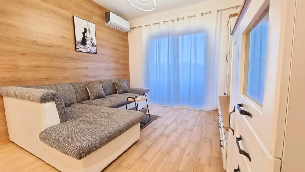 Living room with a sectional sofa, wooden wall panels, and an air conditioner.