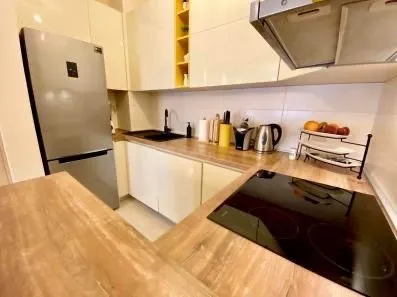 Modern kitchen with wooden elements, refrigerator, and built-in cooktop.