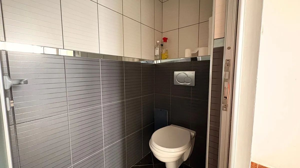 View of the bathroom with a built-in toilet and wall tiles.