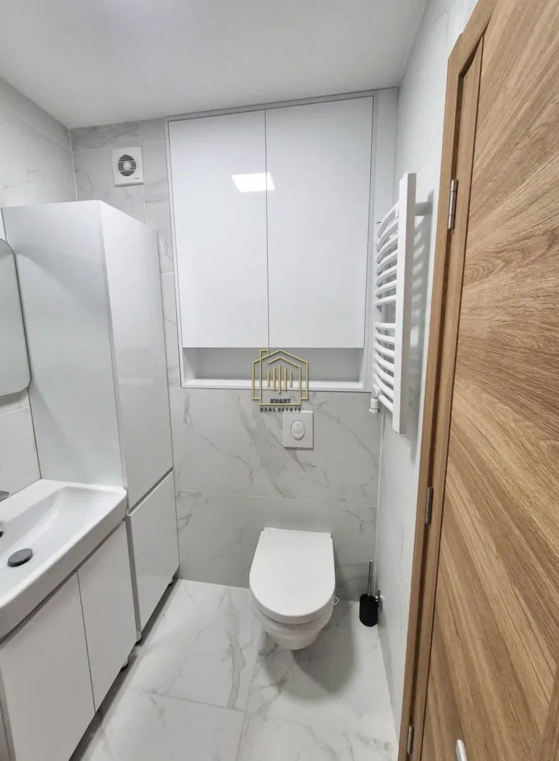 Moderne kupatilo sa bijelim namještajem i keramičkim pločicama sa dezenom mermera.