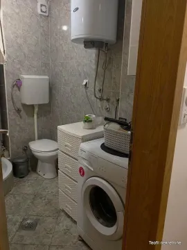 Small bathroom with a washing machine, toilet, and wall-mounted water heater. - image 6
