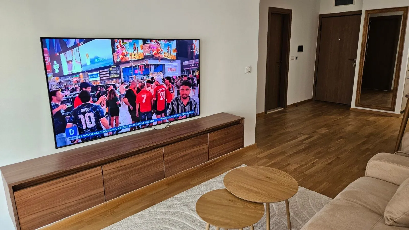 Living room with a large TV, wooden cabinet, and sofa.