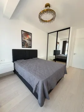 Moderna spavaća soba sa bračnim krevetom, bijelim noćnim stolićima i velikim ogledalom. - image 7