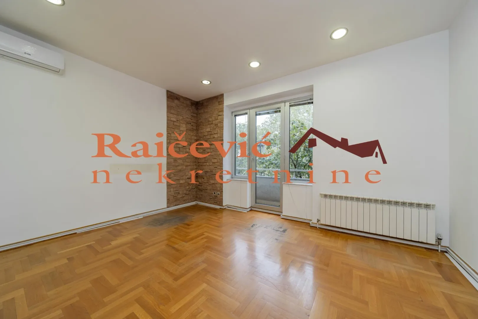 Empty living room with parquet flooring, a brick accent wall, and terrace access.